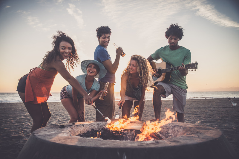 Image of five friends partying around a beach bonfire.