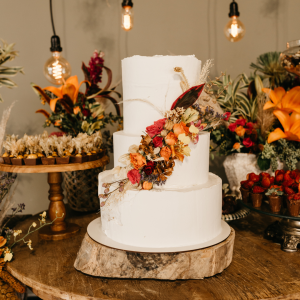 3-tier white wedding cake with fall-inspired floral arrangements