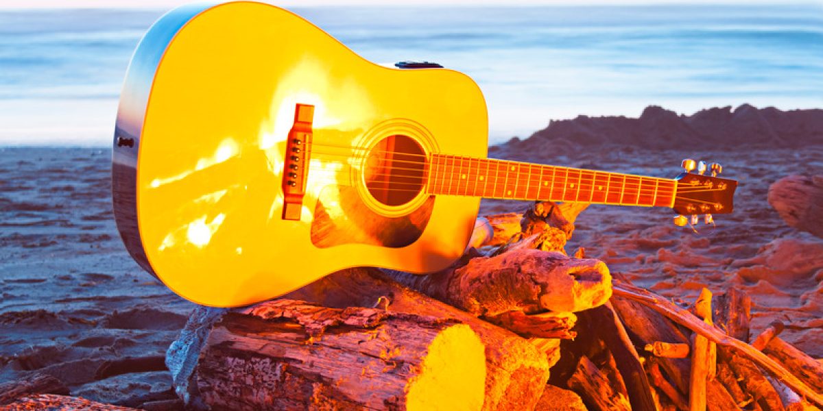 Image of a yellow guitar on a beach bonfire.